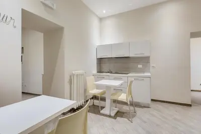 a kitchen with white cabinets and a table and chairs at Vaticano 38 Suites in Rome