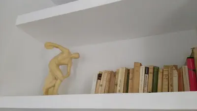 a book shelf with a statue of a man doing at Eluta Holiday Home in Rome