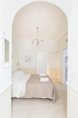 a white bedroom with a bed and a mirror at La Maison de la vie in Rome