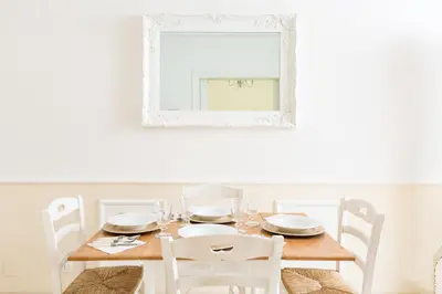 a dining room table with white chairs and a mirror at La Maison de la vie in Rome