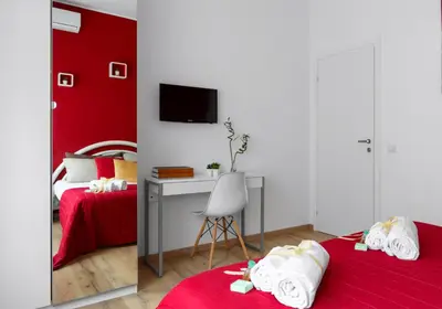 a bedroom with two beds and a desk and a red wall at Homs Sweet Home in Rome