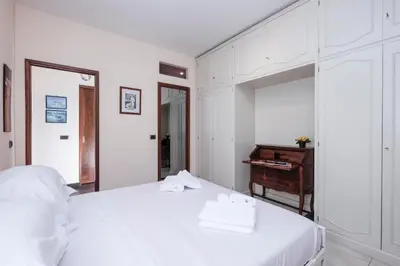 a white bedroom with a bed and a mirror at Monteverde 2BDR Family Apartment in Rome