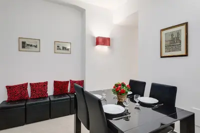 a dining room with a table and a black couch at Prime Vatican Suites in Rome