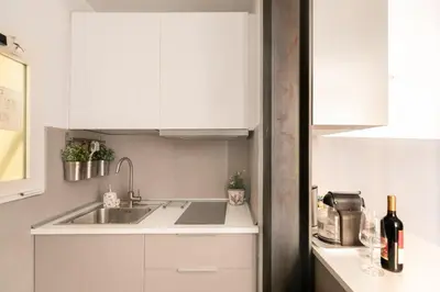 a kitchen with white cabinets and a sink at Living RHome - Condotti Apartment in Rome