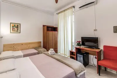 a hotel room with two beds and a desk and a television at Hotel Altavilla 9 in Rome