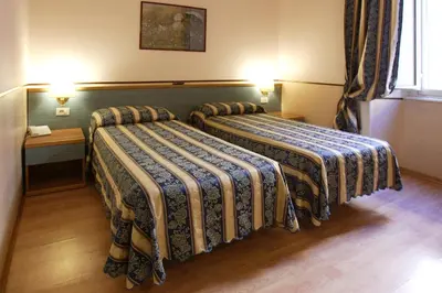 two beds in a hotel room with two lamps at Hotel Lazzari in Rome