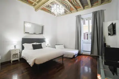 a bedroom with a large white bed and a chandelier at La Maison Dell'Orologio in Rome