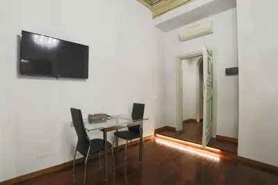 a dining room with a glass table and a television on a wall at La Maison Dell'Orologio in Rome