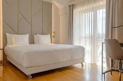 a bedroom with a large white bed and a window at NH Collection Roma Giustiniano in Rome