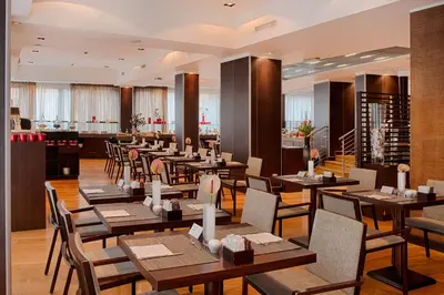 a restaurant with wooden tables and chairs and a bar at NH Collection Roma Giustiniano in Rome