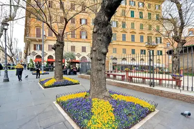 two trees and flowers in front of a building at Parrotshouse in Rome