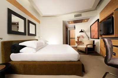 a bedroom with a bed and a chair and a television at Babuino 181 - Small Luxury Hotels of the World in Rome