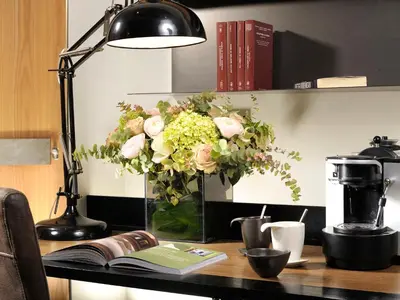 a vase of flowers on a desk with a lamp at Babuino 181 - Small Luxury Hotels of the World in Rome