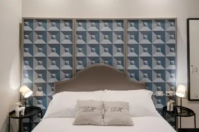 a bed with a large headboard with two pillows on it at Deseo Home Guest House in Rome