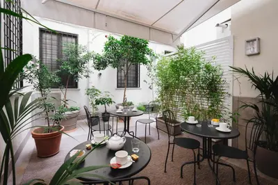 a patio with tables and chairs and potted plants at Deseo Home Guest House in Rome