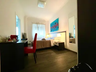 a bedroom with a bed and a desk with a red chair at Your House By Ale in Rome