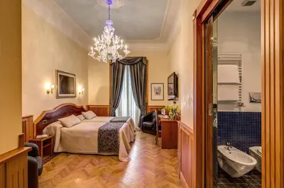 a bedroom with a bed and a bathroom with a chandelier at Relais Conte Di Cavour De Luxe in Rome