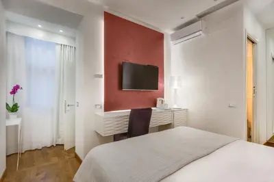 a bedroom with a bed and a desk and a tv at Shali Luxury Suite Spagna in Rome