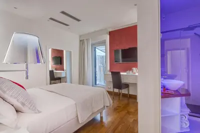 a bedroom with a white bed and a desk with chairs at Shali Luxury Suite Spagna in Rome