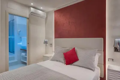 a bedroom with a white bed with a red wall at Shali Luxury Suite Spagna in Rome