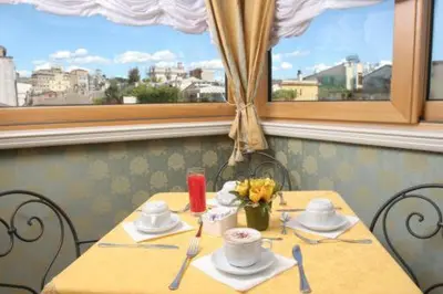 a table in a restaurant with a yellow table cloth and a table with flowers at Hotel La Lumiere Di Piazza Di Spagna in Rome
