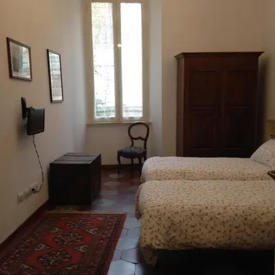 a bedroom with two beds and a chair and a window at Casa in Trastevere in Rome