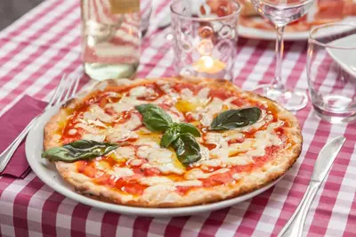 a pizza on a white plate on a table at Monti Garden in Rome