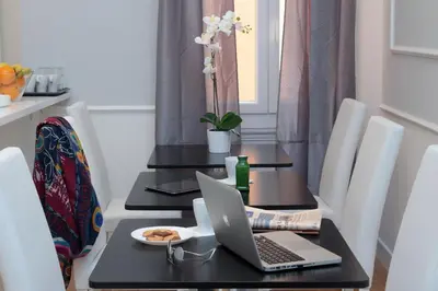a dining room table with a laptop computer on it at St. Peter Vatican Rooms in Rome