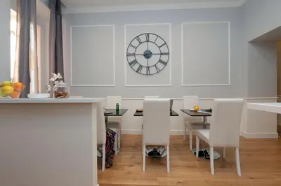 a dining room with a table and a clock on the wall at St. Peter Vatican Rooms in Rome