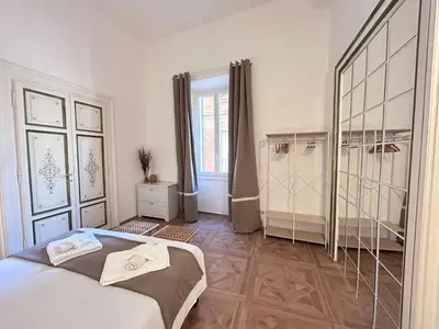 a white bedroom with a large bed and a window at Vicolo Doria Apartment in Rome