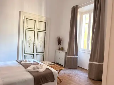 a bedroom with a white bed and a wooden floor at Vicolo Doria Apartment in Rome