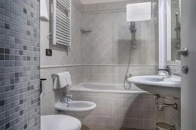 a bathroom with a toilet and a sink and a tub at Hotel Varese in Rome