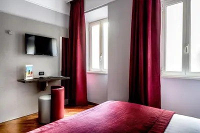 a bedroom with red curtains and a bed and a tv at Hotel Varese in Rome