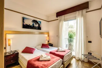two beds in a room with a window at Ginevra Palace Hotel in Rome