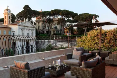 a patio with chairs and tables and an umbrella at Hotel Degli Artisti in Rome