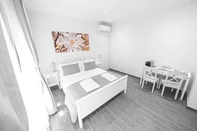 a white bedroom with a bed and a table at BePlace Aventino in Rome