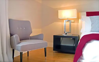 a bedroom with a chair and a table with a lamp at Adamas Luxury Suite in Rome