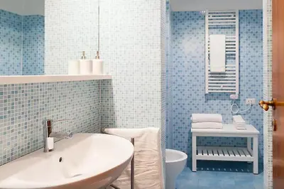 a blue tiled bathroom with a sink and a tub at Exclusive apartment a few steps from the Spanish Steps in Rome