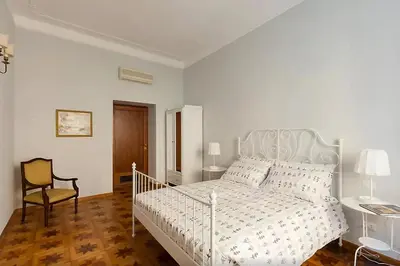 a white bedroom with a bed and a chair at Exclusive apartment a few steps from the Spanish Steps in Rome
