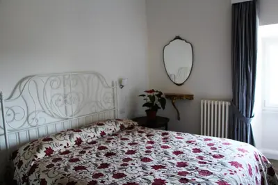 a bedroom with a bed with a floral bedspread and a mirror at La Rosa del Vaticano Luxury Apartment in Rome