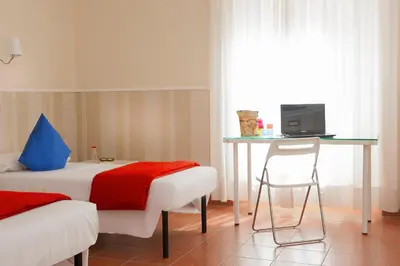 a bedroom with a bed and a desk and a chair at Budget Rooms Des Arts in Rome