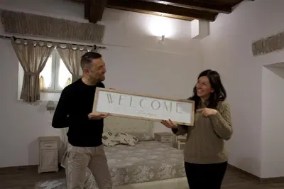 a man and woman holding a welcome sign in a bedroom at Navona Sweet Home in Rome
