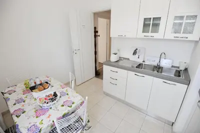 a kitchen with white cabinets and a table with a crib at Le Fontane di Roma in Rome