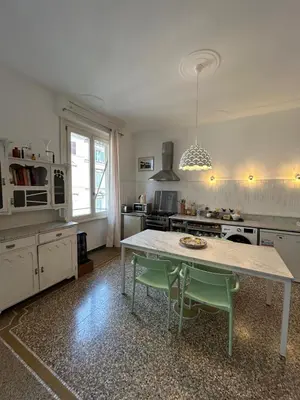 a kitchen with a table with two green chairs at Our Home in Rome - Via Machiavelli in Rome