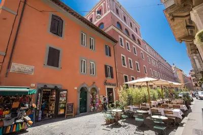 a street with tables and umbrellas in front of a building at Piccolo Trevi Suites in Rome