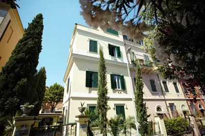 a large white building with green shuttered windows at Residenza Matilde in Rome