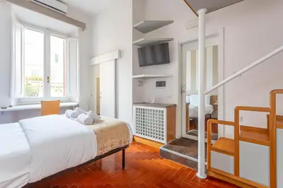 a white bedroom with a bed and a bathroom at Easybnb - Dea Roma in Rome