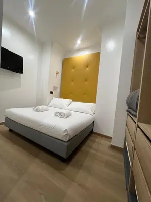 a bedroom with a bed with a yellow headboard at Hotel Ercoli House in Rome
