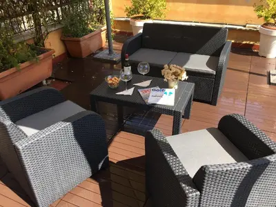 a patio with chairs and a table with a bottle of wine at La Piazzetta di Roma in Rome
