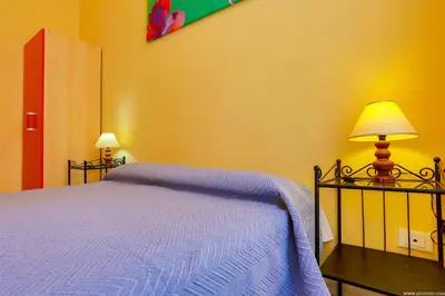 a bedroom with a bed with a blue blanket and a lamp at Gordon's Apartment in Rome